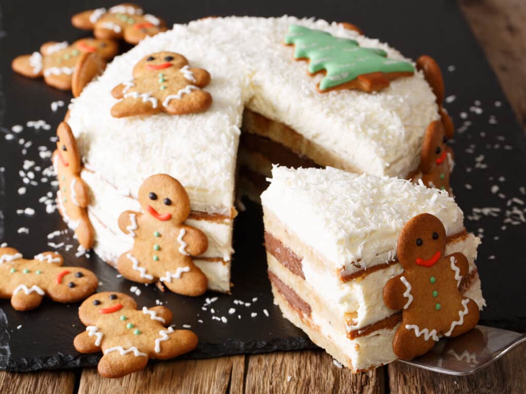 piece of Christmas cake with cheese cream is decorated with gingerbread close-up on the table. horizontal