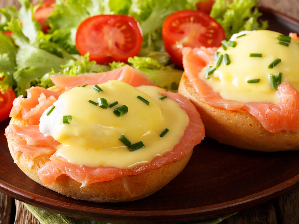 poached eggs with smoked salmon, hollandaise sauce and fresh vegetables close-up on a plate. horizontal