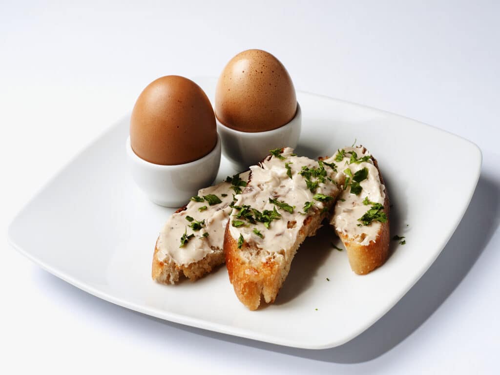 Eggs and open sandwich with toasted rustic bread and home made aromatic anchovy butter