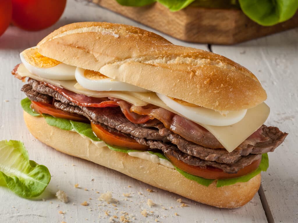 Chivito is a typical sandwich from Uruguay, with lettuce, tomato, bacon, beef, fried or boiled eggs and cheese.