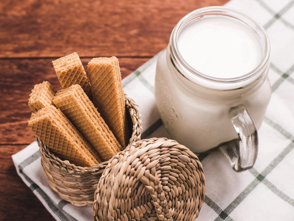 Milk and wafer on wooden background. Concept for break time, morning lifestyle, breakfast.