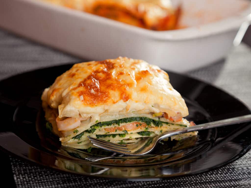 Typical Italian lasagna with spinach and salmon. Baking dish on background