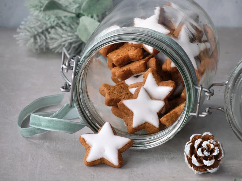 Christmas background with tasty star ginger cookies in a glass jar with winter decorations, copy-space