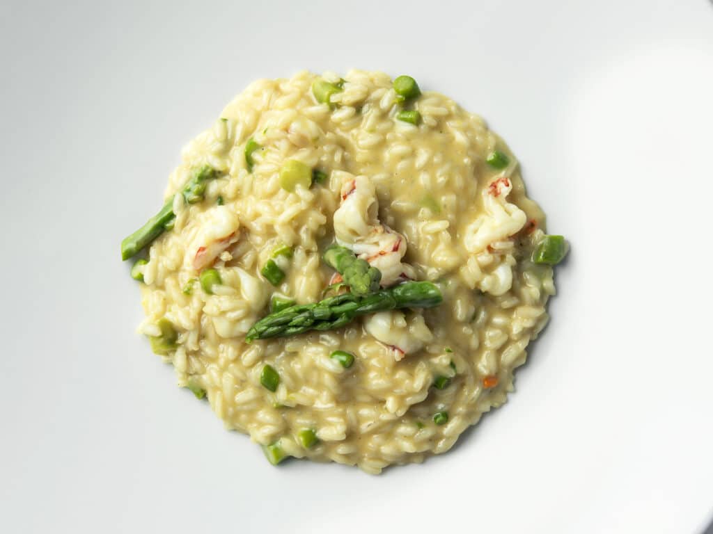 Top view of Plate of Risotto with green asparagus and prawns isolated on white background