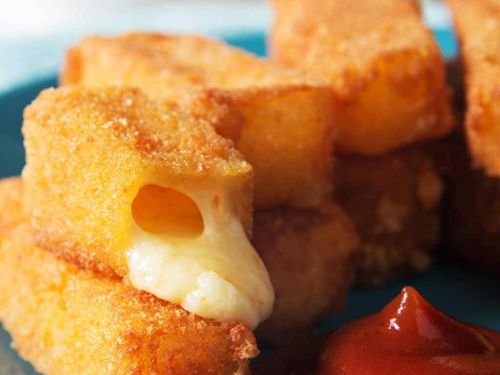 Vertical photo of fried cheese sticks with sauce