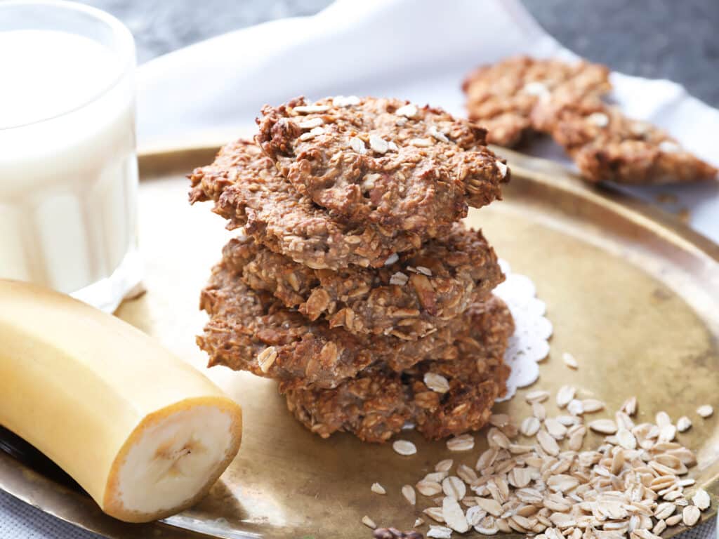 Plate with delicious oatmeal cookies and banana on table, closeup