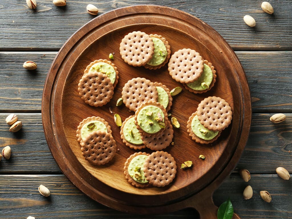 Plate with tasty pistachio cookies on wooden table